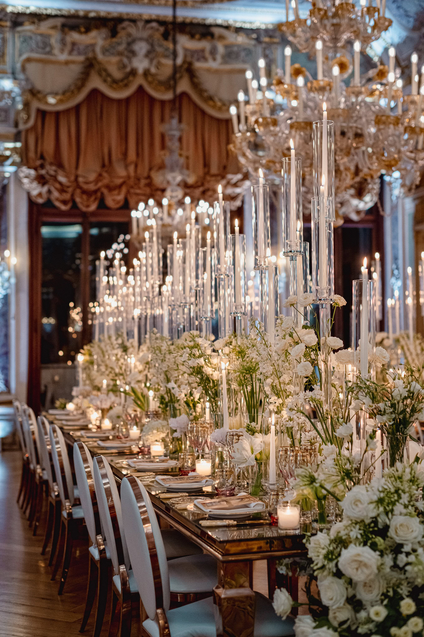 Elegant wedding reception in Venice with a luxurious floral centerpiece and shimmering chandeliers under warm ambient li.