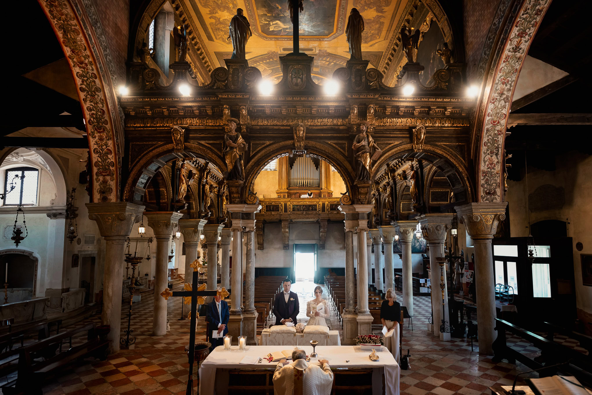A couple exchanging vows inside an ornate Venetian church with golden accents, intricate architecture, and warm ambient.