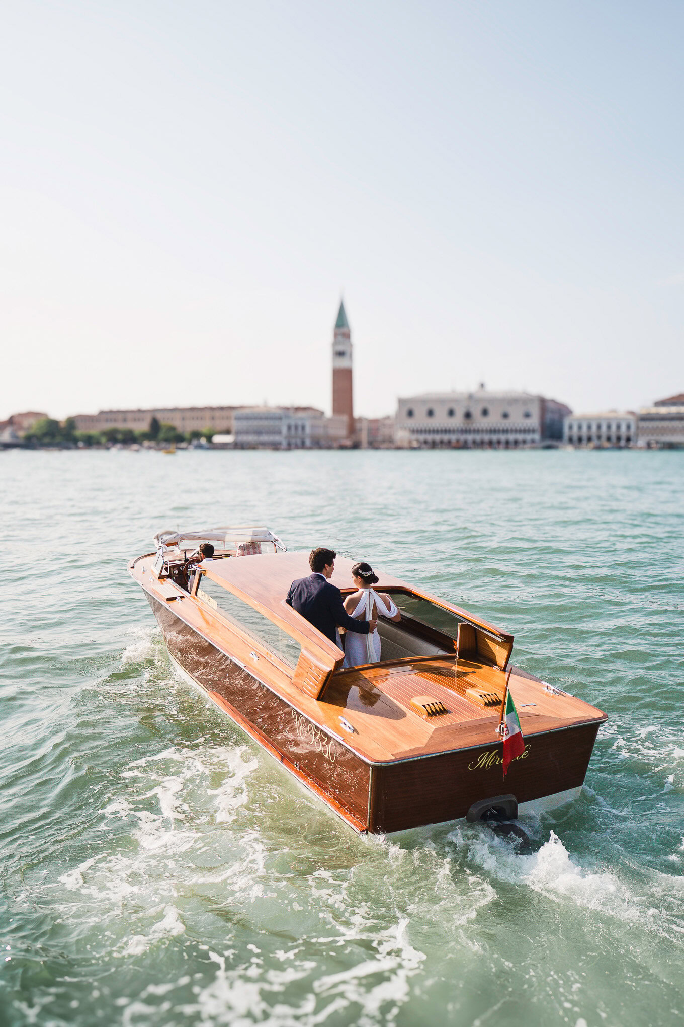 A beautiful scene of a couple enjoying a romantic boat ride on Venice's canals with historic architecture and the bell t.