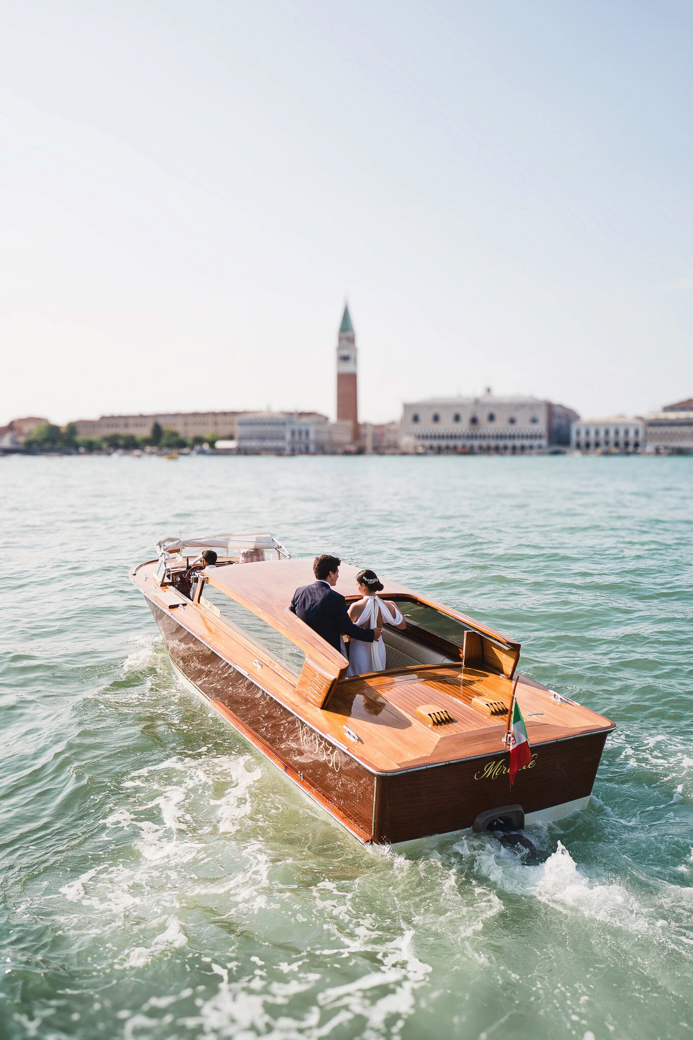 A beautiful scene of a couple enjoying a romantic boat ride on Venice's canals with historic architecture and the bell t.