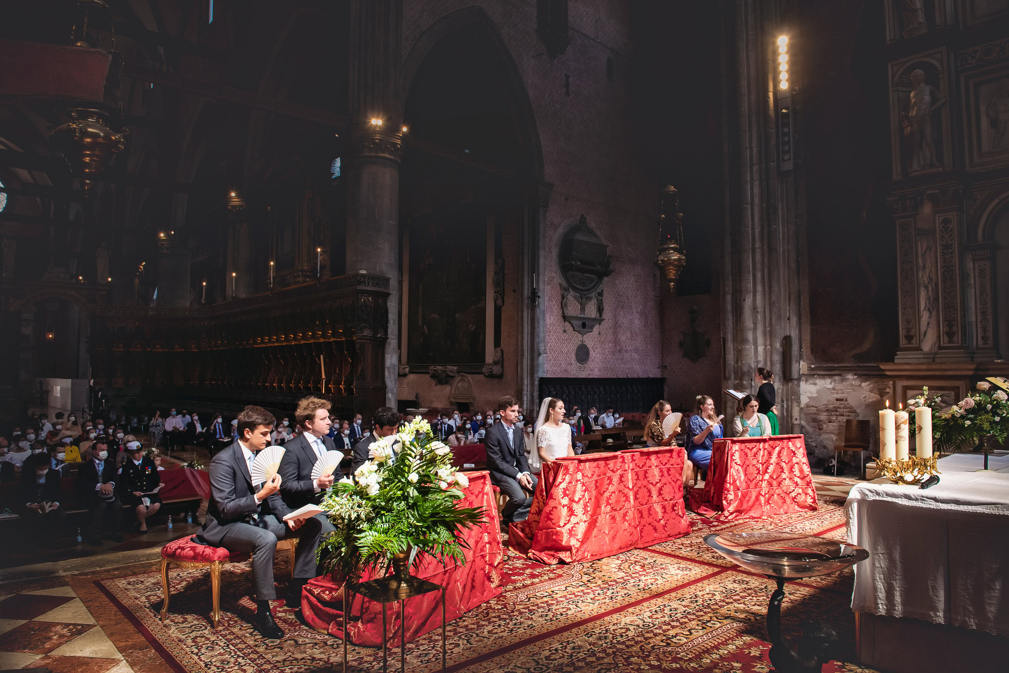 Elegant wedding ceremony inside a historic Venetian church with soft lighting and attentive guests seated on ornate chai.