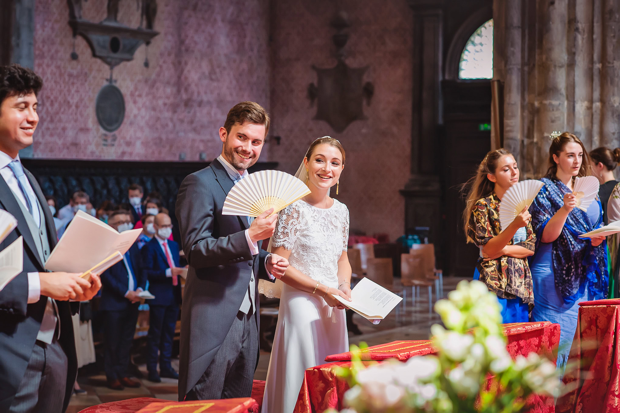 A couple smiles joyfully during their wedding ceremony in a historic Venetian church, illuminated by soft, warm light.