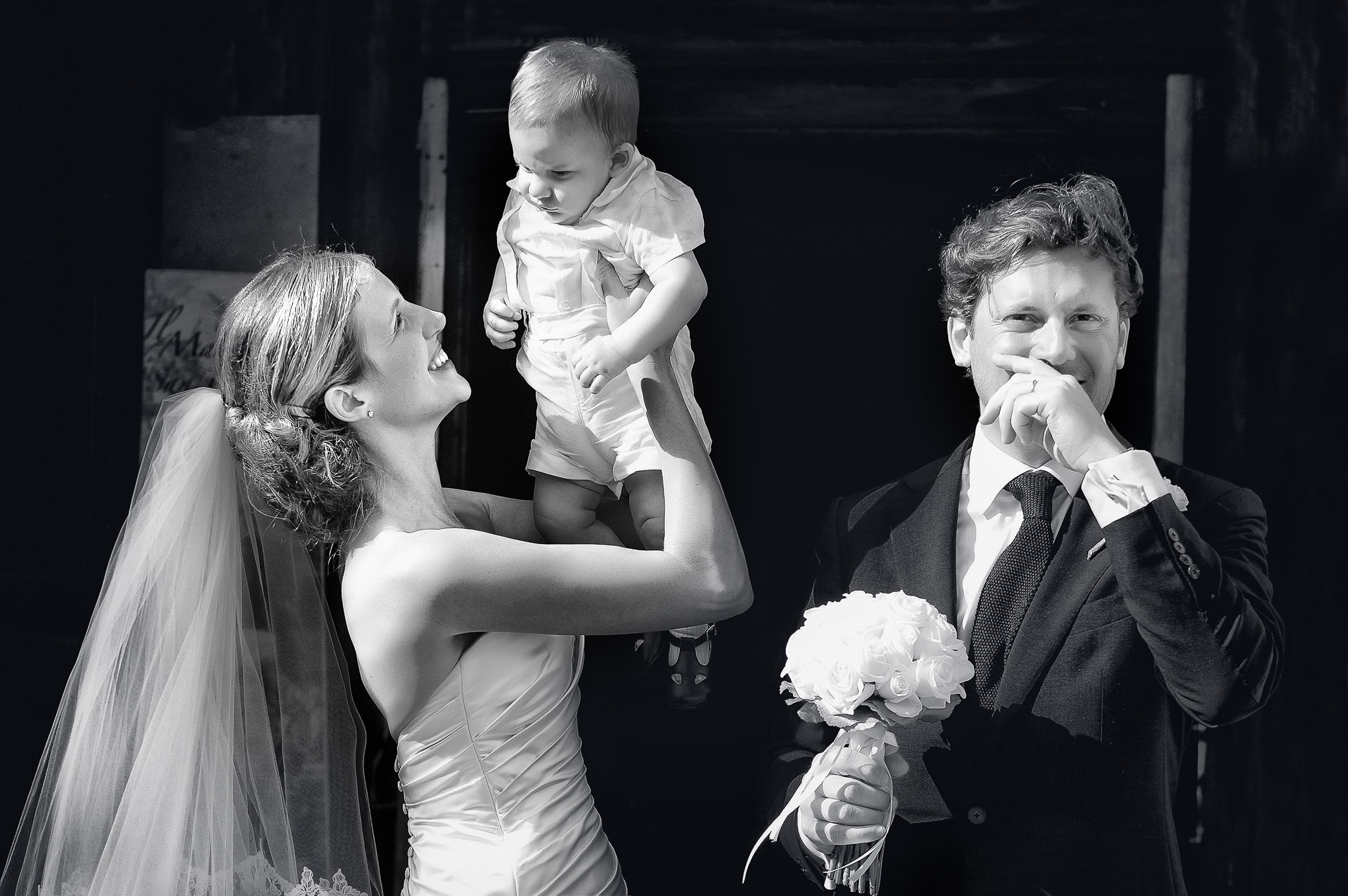 Elegant wedding moment in Venice with bride, groom, and child, captured in soft natural light, highlighting joyful famil.