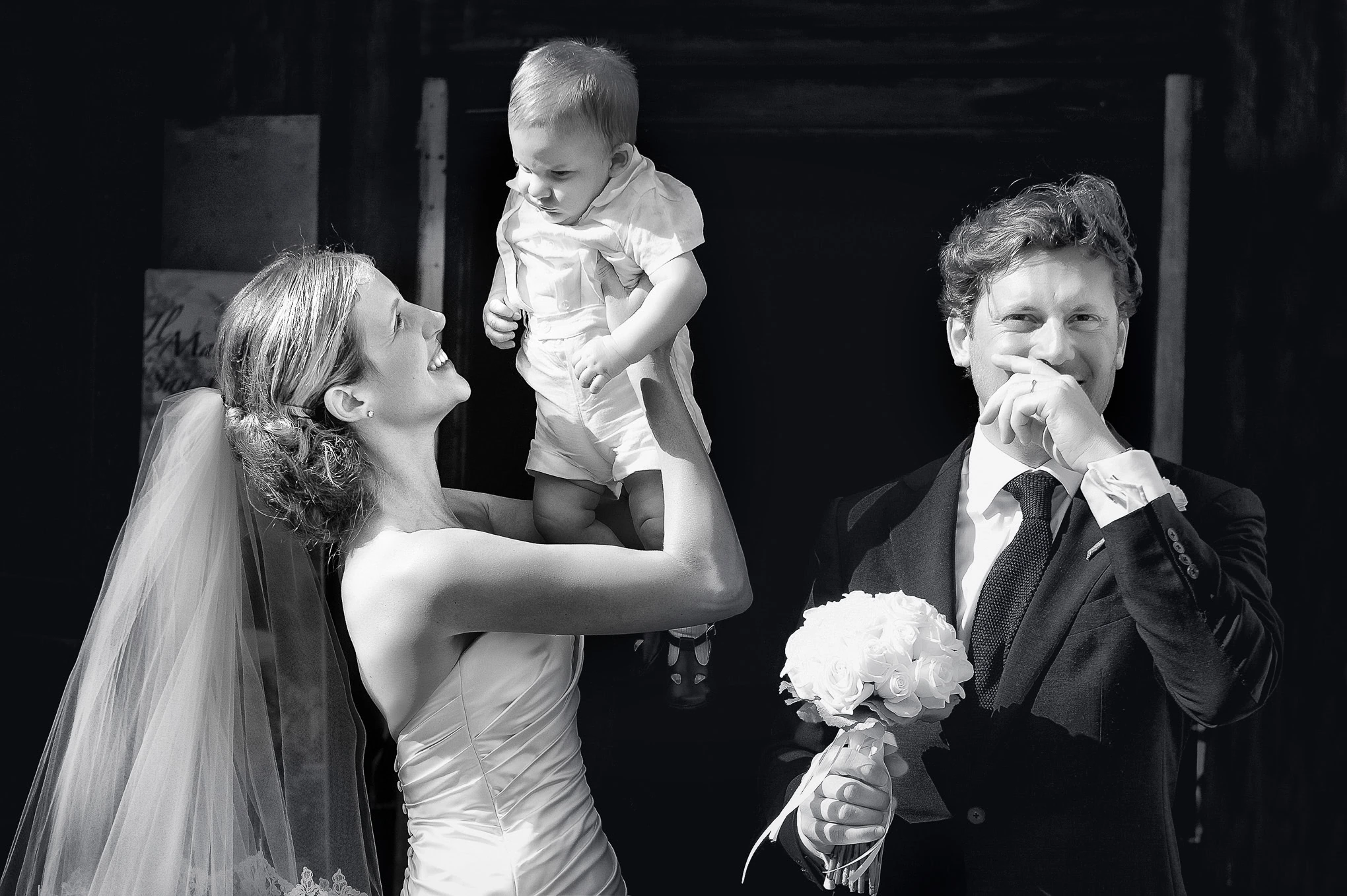 Elegant wedding moment in Venice with bride, groom, and child, captured in soft natural light, highlighting joyful famil.