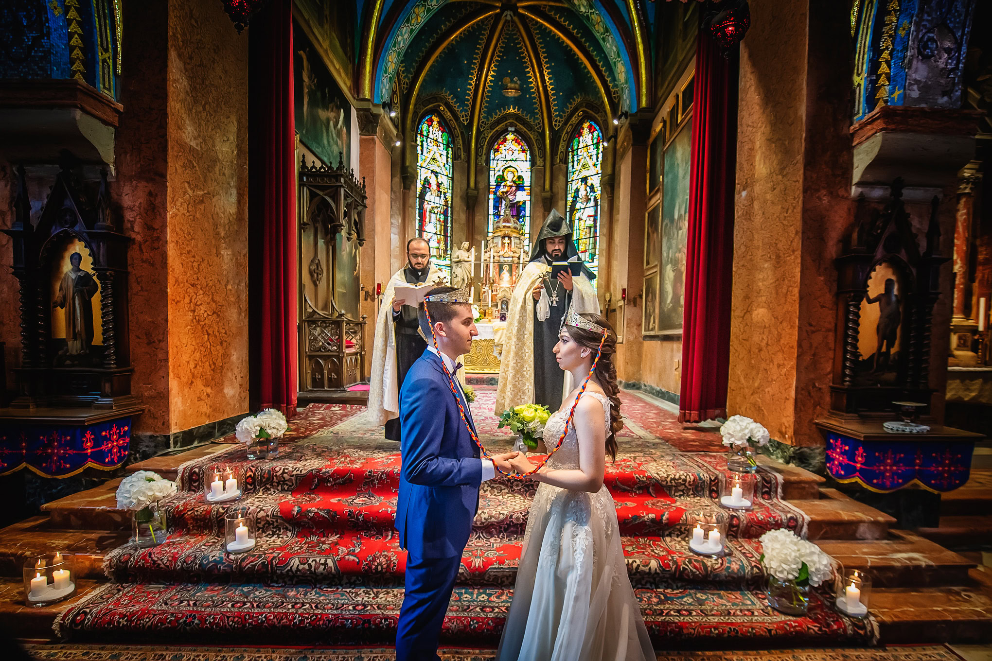 A couple exchanging vows inside a richly decorated Venetian church with vibrant stained glass windows and ornate details.