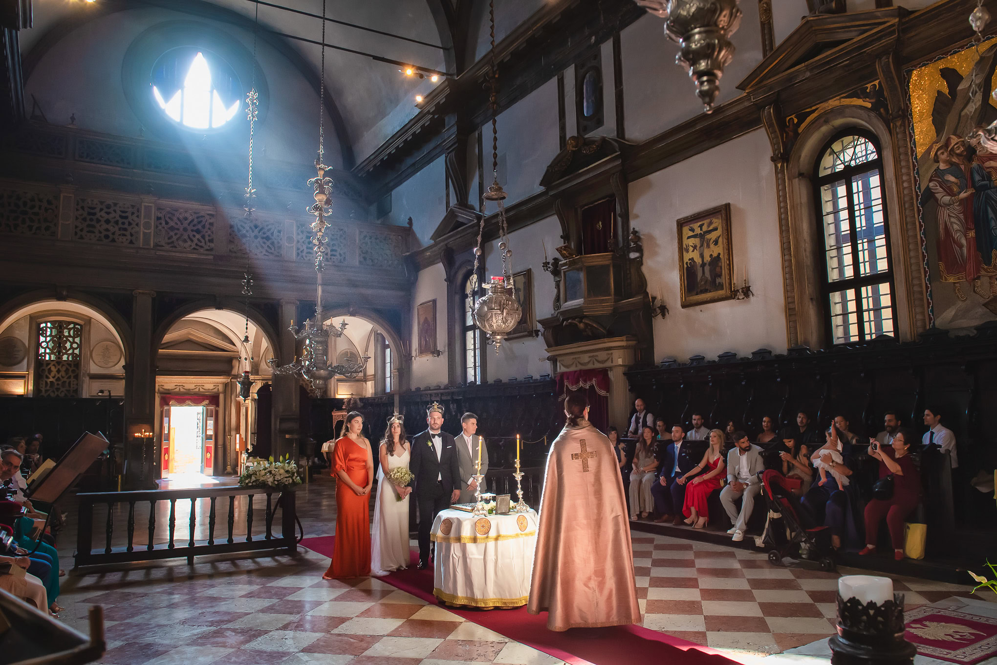 Elegant wedding ceremony inside a historic Venetian church with soft natural light illuminating the scene.
