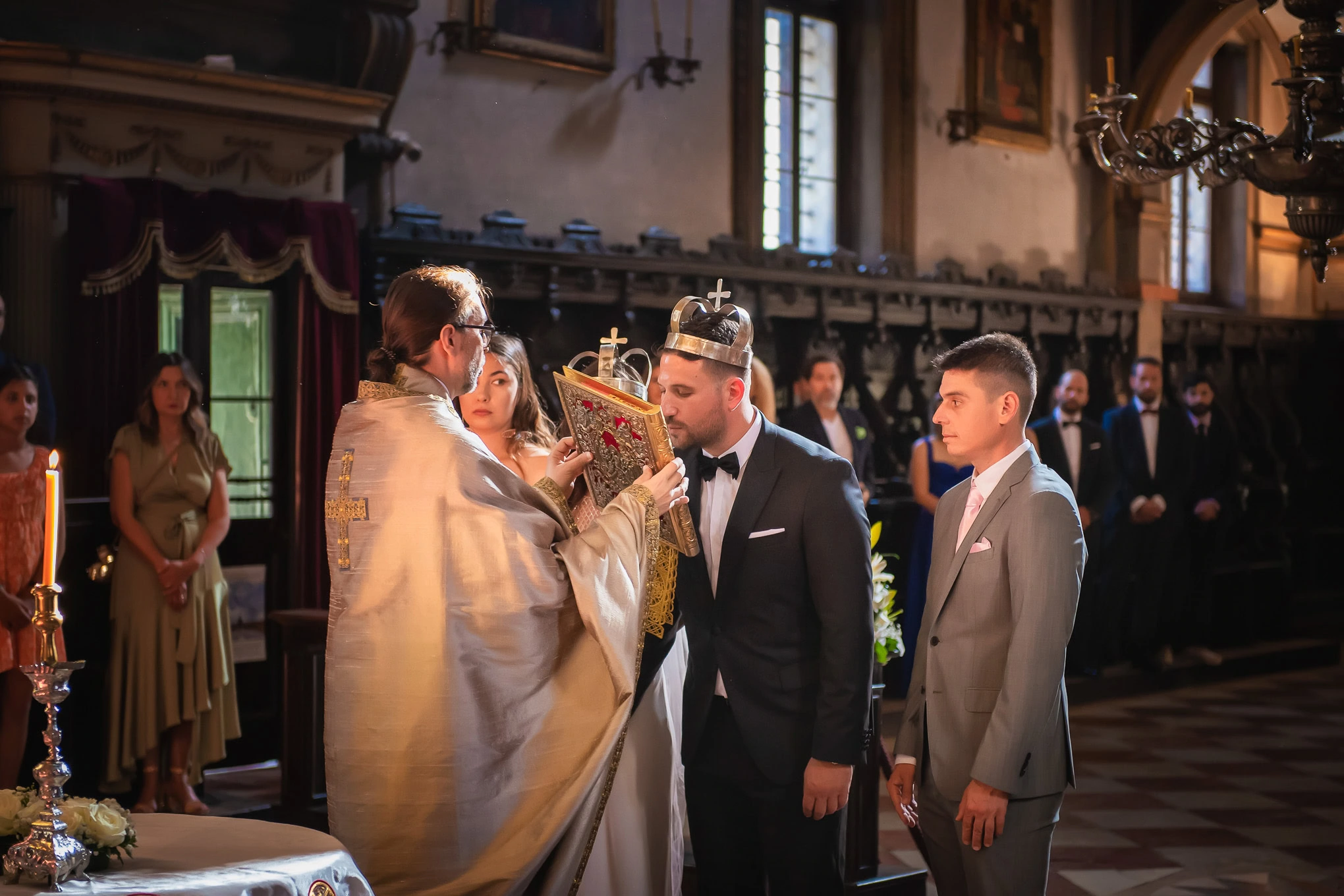 An elegant wedding ceremony in Venice featuring a priest blessing the bride and groom inside a historic church with warm.