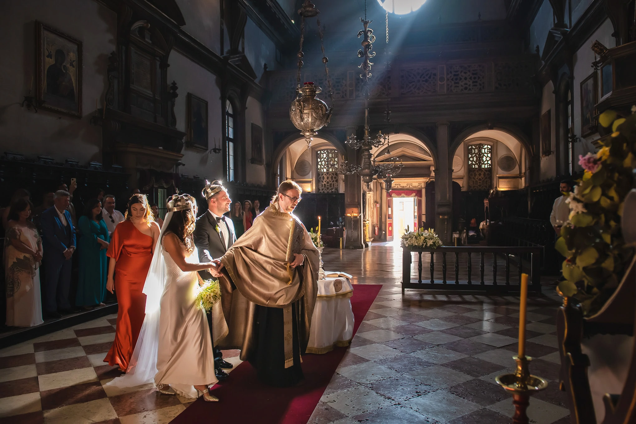 Elegant wedding ceremony inside a historic Venetian church with soft natural light illuminating the couple and officiant.