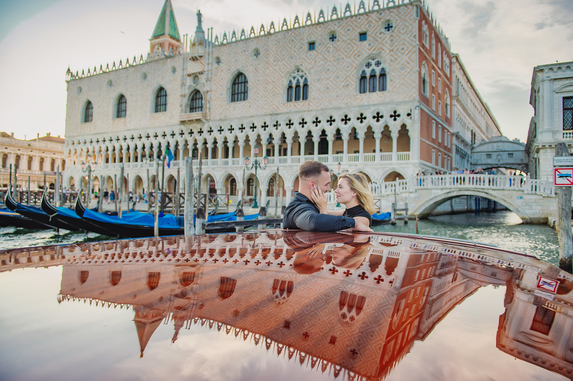 Romantic couple proposing in Venice with the Doge's Palace in the background, during sunset on a gondola.