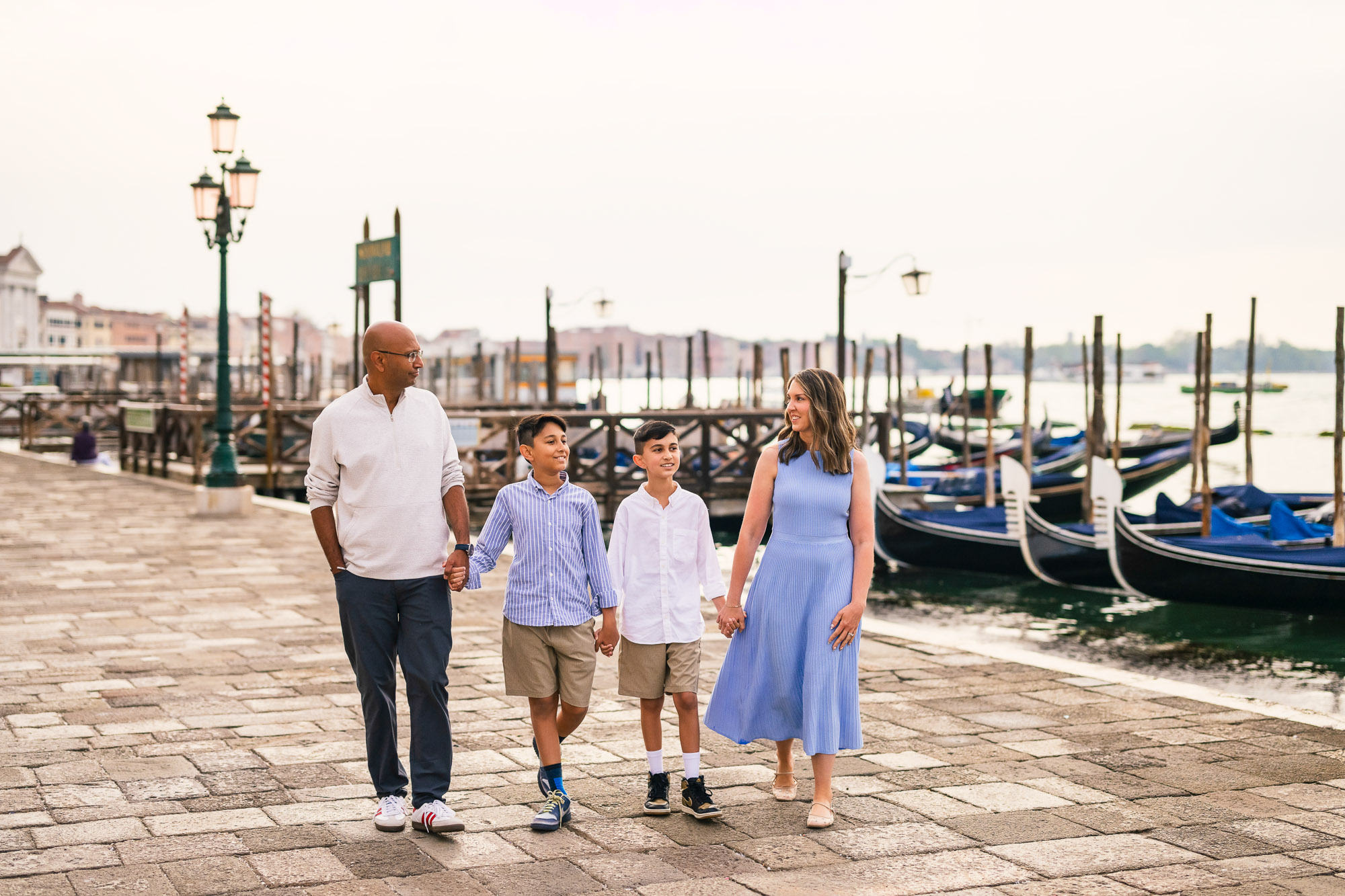 Family walking along Venice waterfront with children, child smiling, parents with children, child looking at camera, in.