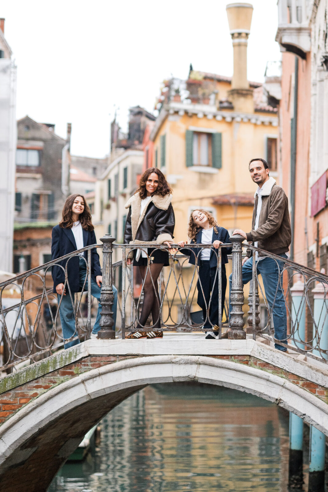 Venice Grand Canal bridge with a family walking, child smiling, parents with children, child looking at camera during da.