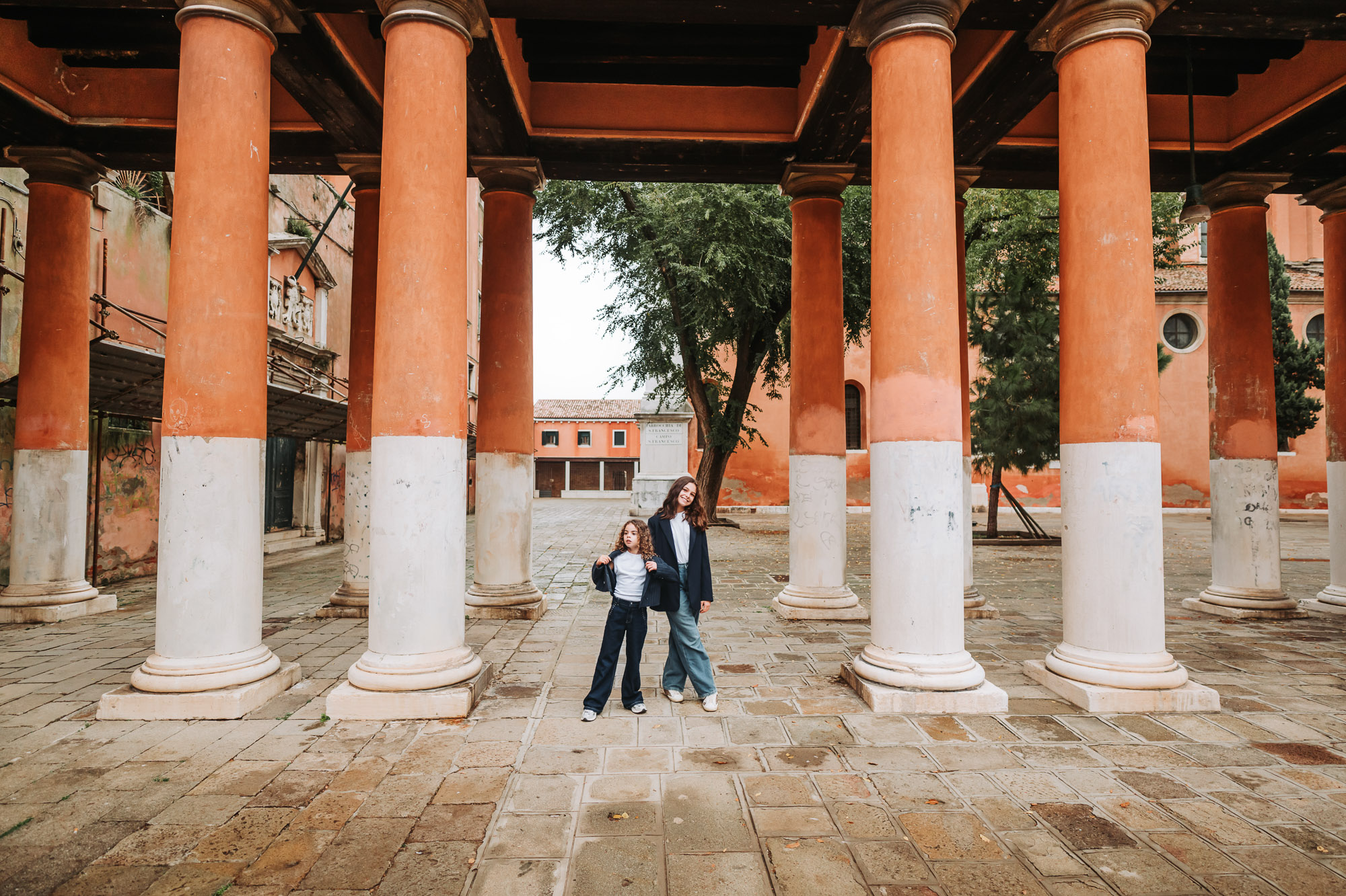 Colorful Venetian columns in the San Polo district with a family walking and a child smiling, during daytime with soft n.