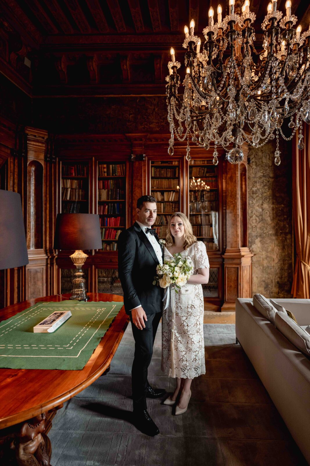 Venetian Church wedding couple in elegant attire, luxurious interior with chandelier and wooden bookshelves.