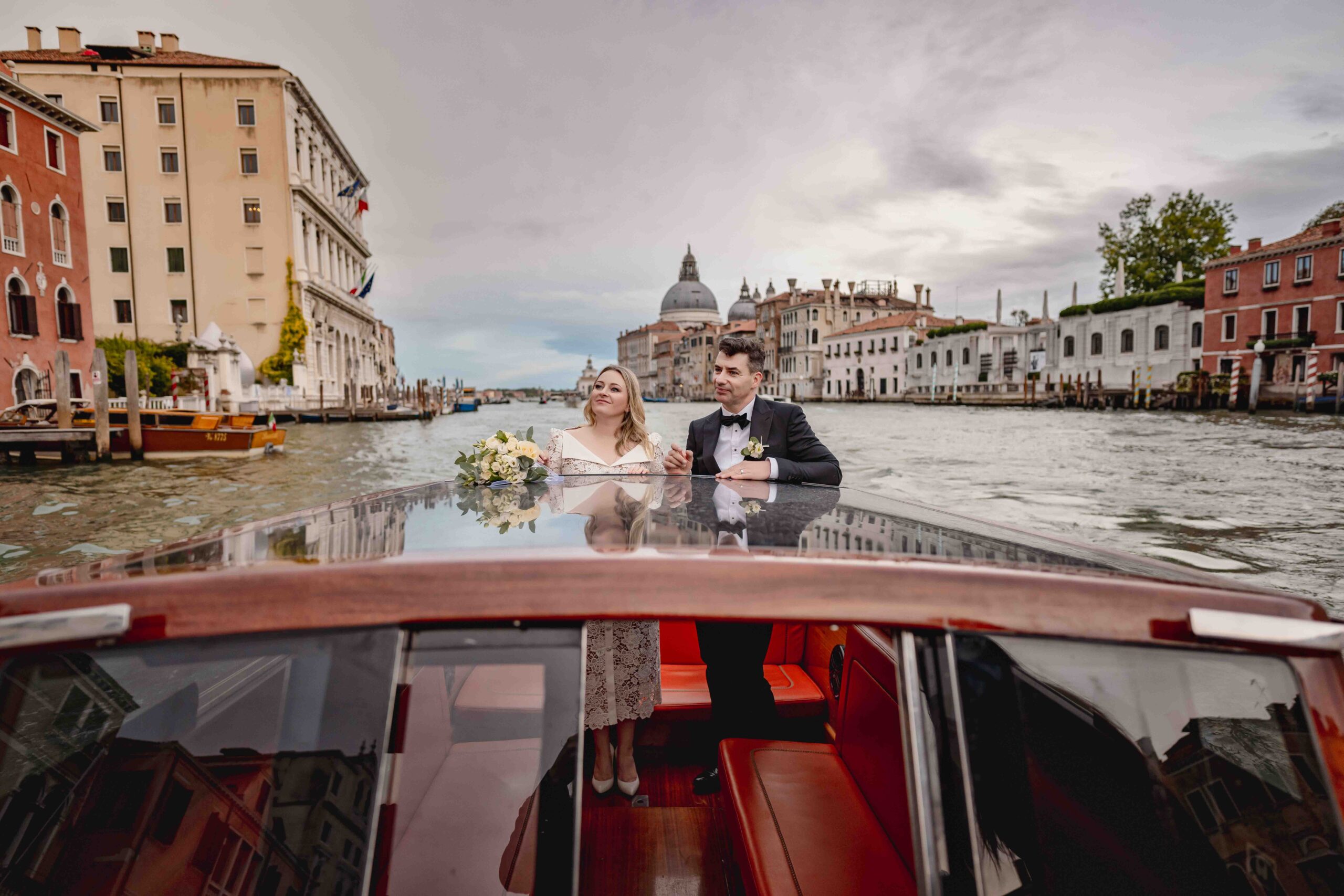 Venice church wedding scene with bride and groom on a boat, historic buildings, and canal backdrop.