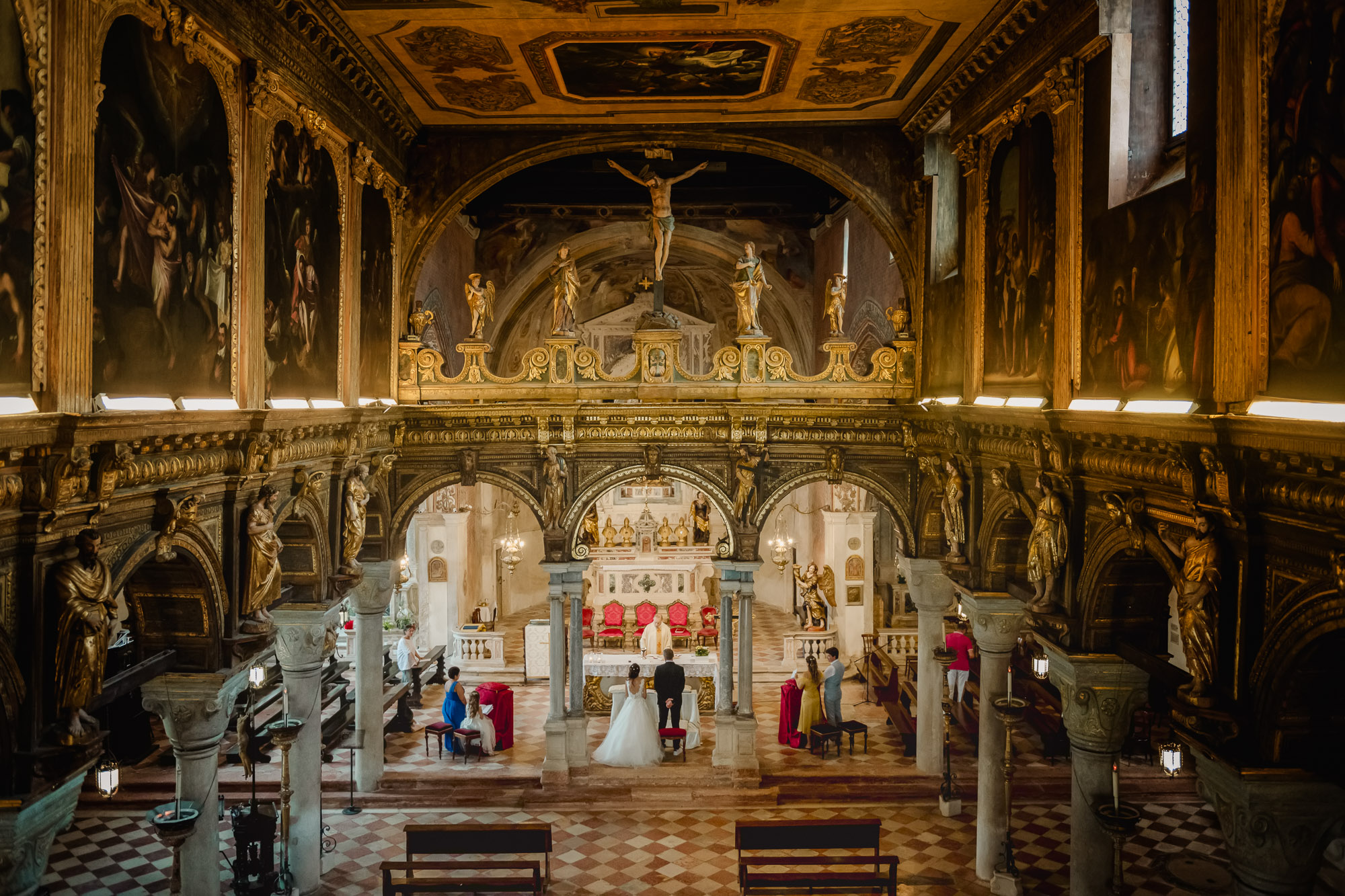 Venice church interior during a Catholic wedding ceremony with the bride and groom at the altar.