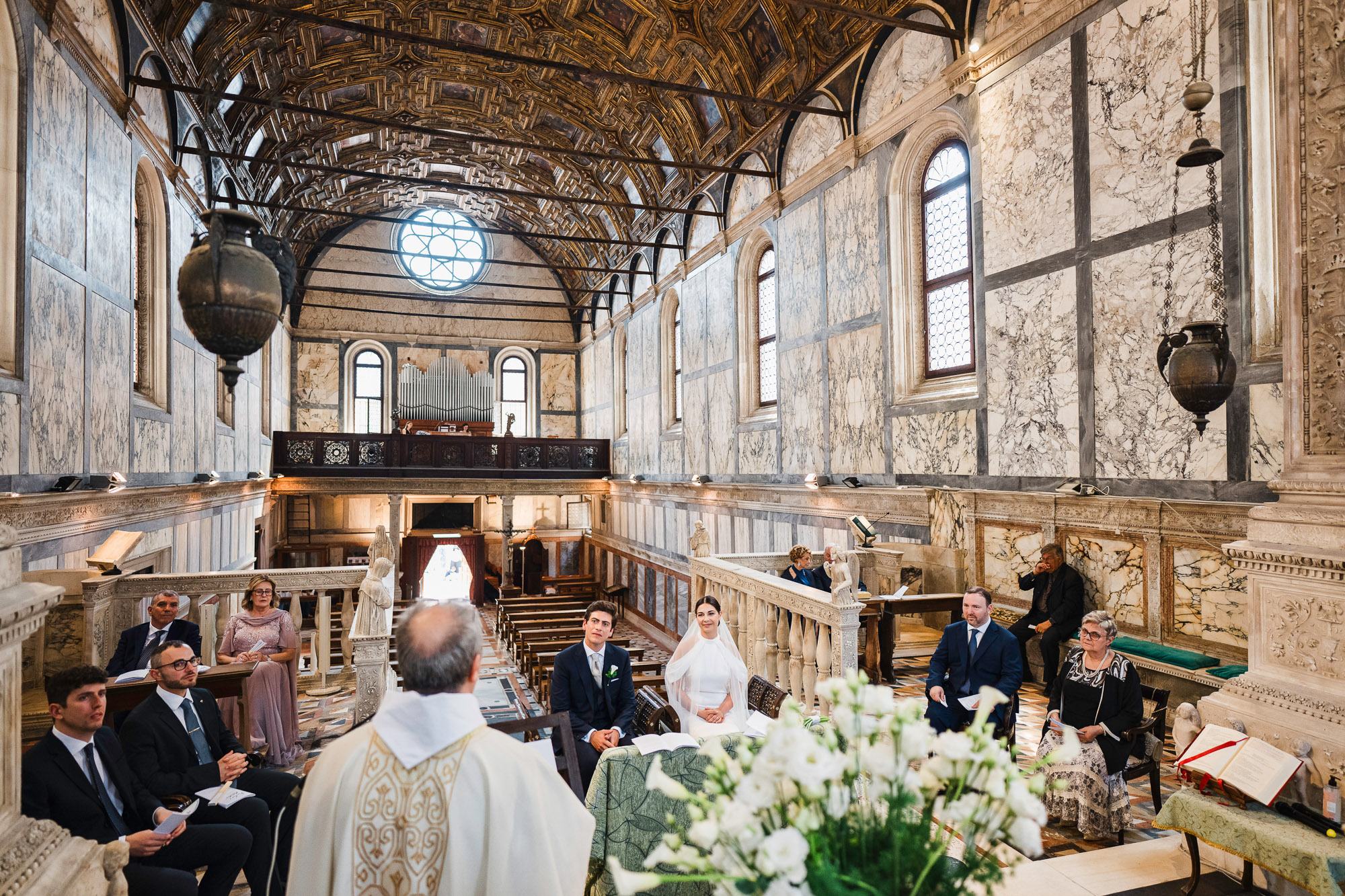 Venice church interior during a Catholic wedding ceremony with the priest officiating.
