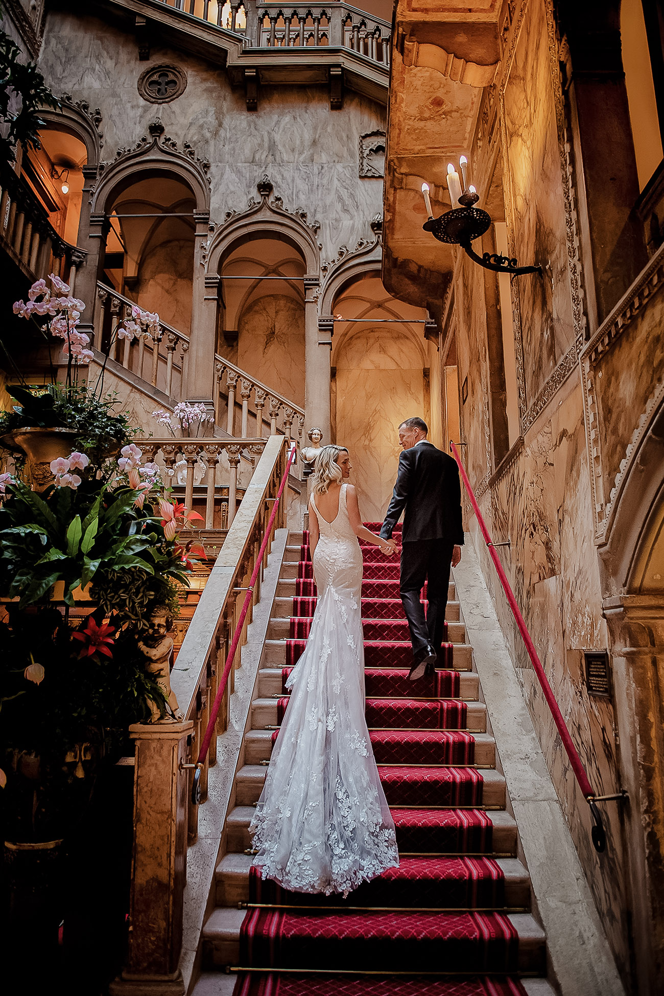 Elopement couple ascending grand staircase inside ornate Venetian palazzo