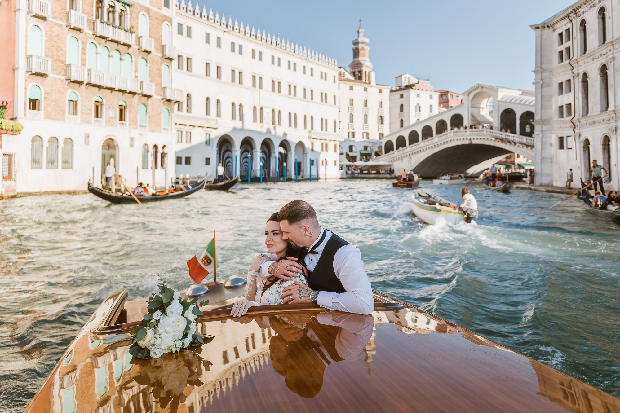 Romantic Venice elopement photo of couple kissing on a gondola with historic buildings in the background.