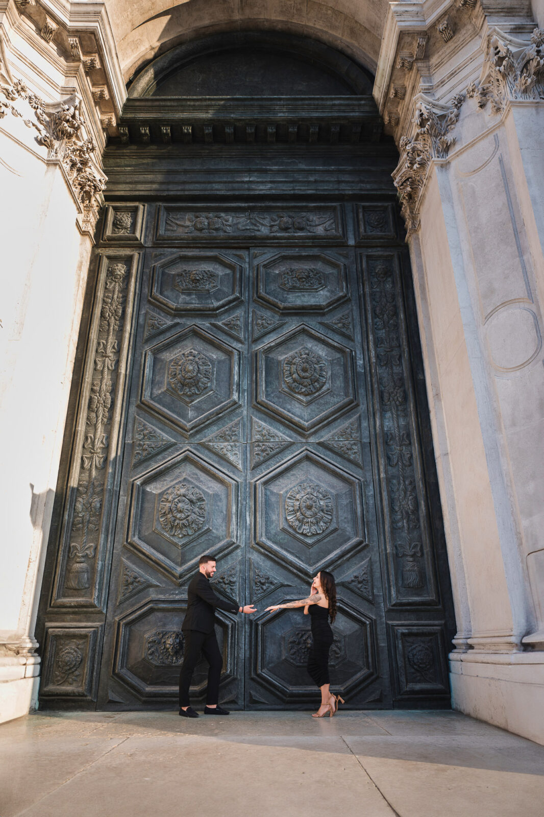 A large, ornate door with intricate carvings and architectural details, set within a historic building facade.
