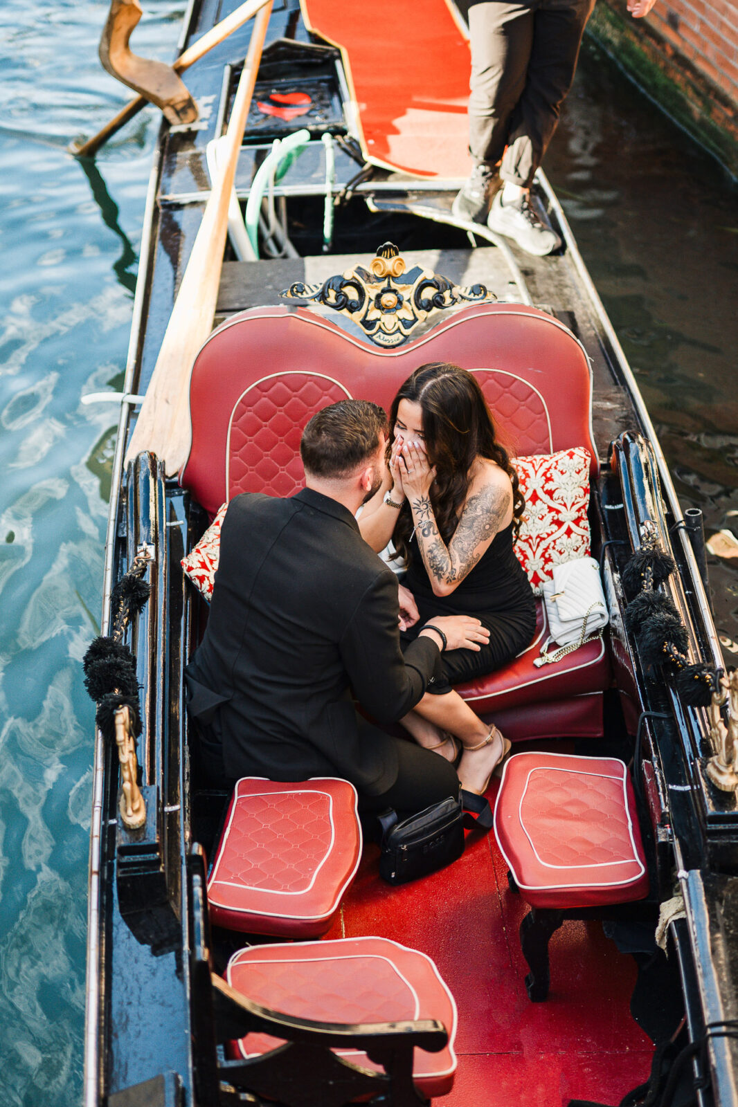 A couple sharing a romantic moment on a gondola in Venice during a proposal.