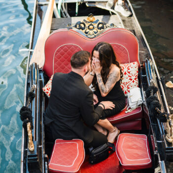 A couple sharing a romantic moment on a gondola in Venice during a proposal.