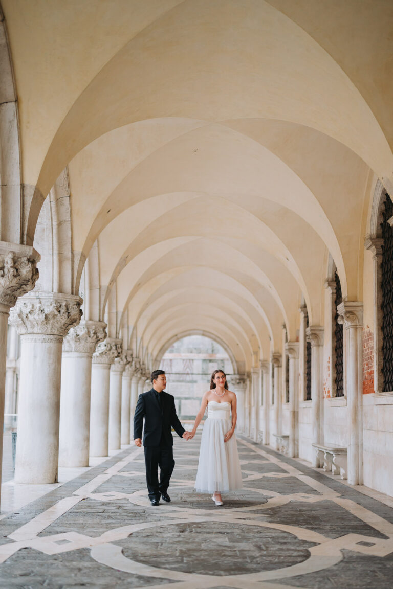 honeymoon couple walking under Venetian arcade during sunrise photoshoot