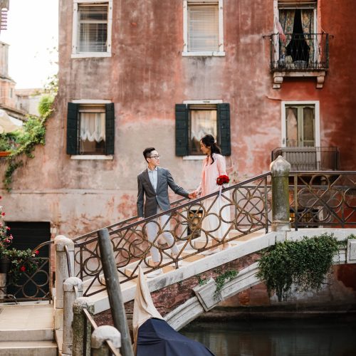 engagement-photography-portfolio-in-venice–25 A couple walking hand in hand on a Venetian bridge in a charming, historic neighborhood.