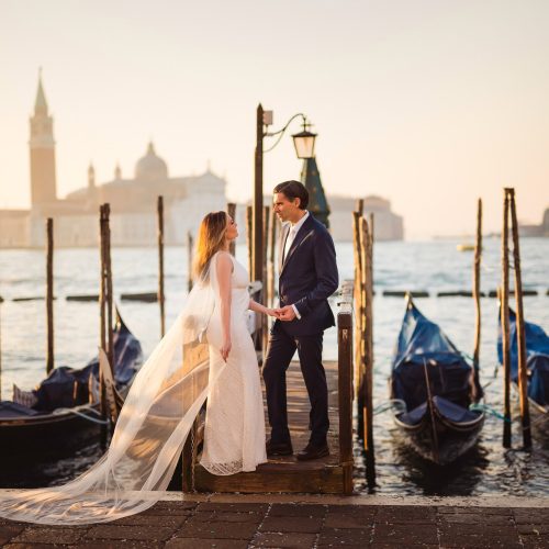 A couple sharing a romantic moment by the water in Venice during golden hour.