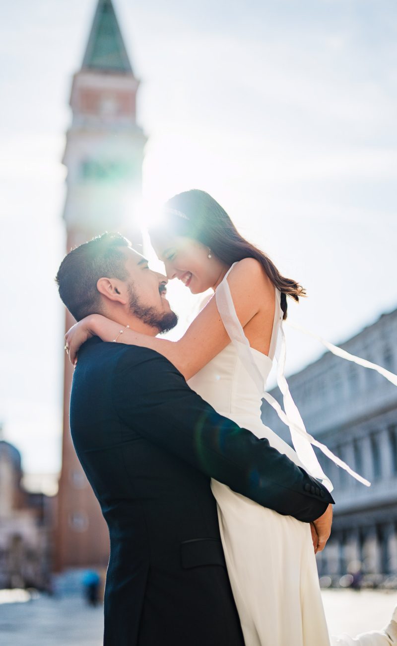 honeymoon couple kissing in front of St Mark’s Campanile Venice