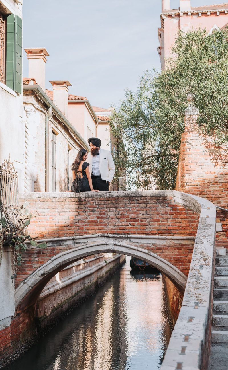 Elopement couple standing on brick bridge above canal in quiet Venice setting